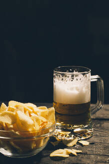 Ein Glas Bier mit einer Schale Kartoffelchips - BLEF14421