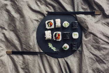 Nahaufnahme einer Sushi-Platte mit Stäbchen im Bett - BLEF14428