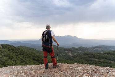 Älterer Wanderer mit Wanderstock auf einem Aussichtspunkt stehend - AFVF03799