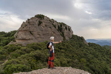 Hiker showing with hiking pole, standing on viewpoint - AFVF03803