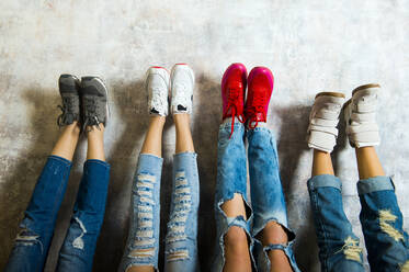 Caucasian women admiring their sneakers against wall - BLEF14451