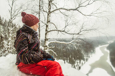 Caucasian hiker sitting on snowy hilltop - BLEF14460