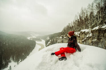 Caucasian hiker sitting on snowy hilltop - BLEF14462