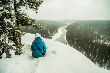 Kaukasischer Wanderer auf einer verschneiten Bergkuppe sitzend - BLEF14463