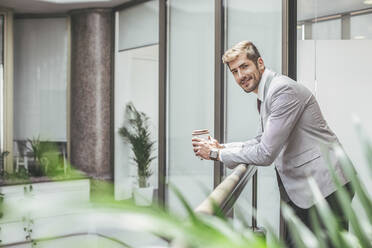 Caucasian businessman drinking coffee on office balcony - BLEF14496