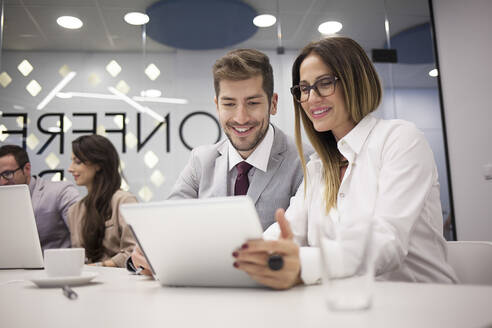 Kaukasische Geschäftsleute benutzen ein digitales Tablet in einer Bürobesprechung - BLEF14507
