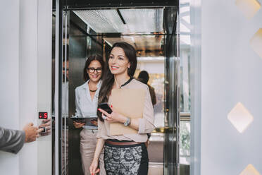 Caucasian businesswomen walking out of elevator - BLEF14511