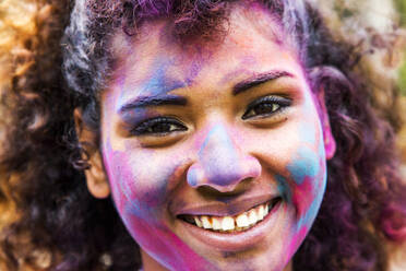 Lächelnde Frau gemischter Rasse, bedeckt mit Pigmentpulver - BLEF14542