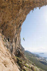 Caucasian climber hanging from cable on rock wall - BLEF14548