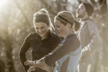 Caucasian runners checking fitness watch in forest - BLEF14555