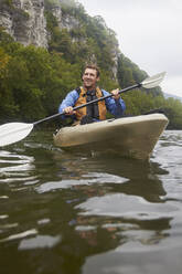 Kaukasischer Mann paddelt Kajak auf einem abgelegenen Fluss - BLEF14561