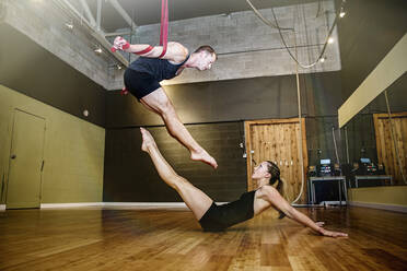 Caucasian acrobats training on ropes in studio - BLEF14591