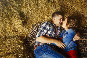 Caucasian couple kissing in haystacks - BLEF14612