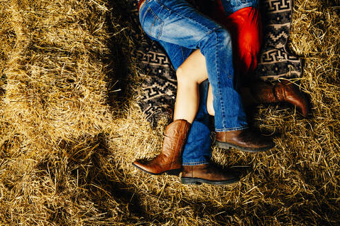 Caucasian couple laying on haystacks - BLEF14613