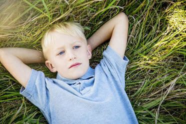 Serious Caucasian boy laying in tall grass - BLEF14626
