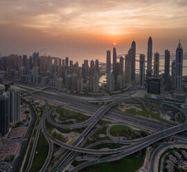 Luftaufnahme des Hafens von Dubai mit Wolkenkratzern, Verkehrslinien und der Palm Jumeirah im Hintergrund bei Sonnenuntergang, Vereinigte Arabische Emirate. - AAEF01746