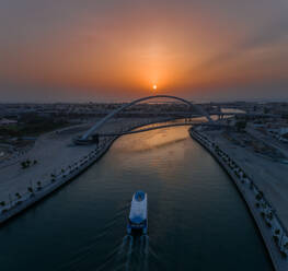 Aerial view of a boat under the Tolerance pedestrian Bridge in Dubai at sunset, U.A.E. - AAEF01766