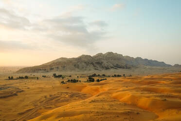 Luftaufnahme eines Berges inmitten der Wüste bei Sonnenuntergang, Vereinigte Arabische Emirate - AAEF01935