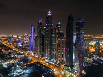 Luftaufnahme von beleuchteten Wolkenkratzern bei Nacht in Dubai, Vereinigte Arabische Emirate. - AAEF01978