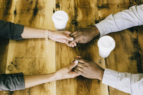 Black couple holding hands at wooden table, - BLEF14644