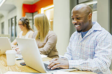 Geschäftsleute arbeiten an Laptops in einer Bürobesprechung - BLEF14662