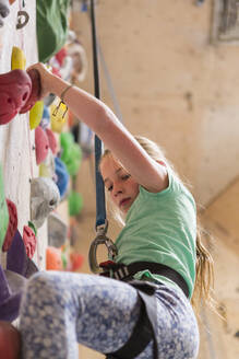 Caucasian girl climbing rock wall indoors - BLEF14677