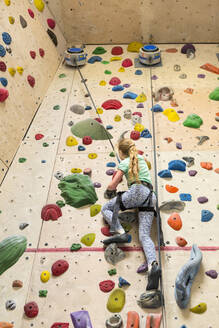 Caucasian girl climbing rock wall indoors - BLEF14678