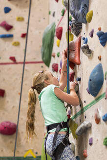 Caucasian girl climbing rock wall indoors - BLEF14679