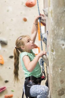 Caucasian girl climbing rock wall indoors - BLEF14682