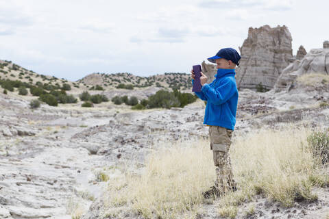 Junge fotografiert Felsformationen in der Wüstenlandschaft, lizenzfreies Stockfoto