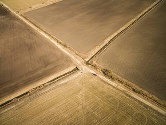 Aerial view of a car parked on a straight empty road in the middle of farmland in Estonia. - AAEF02023