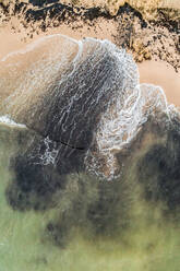 Aerial view of the baltic sea crashing on the black sand of the beach in Estonia. - AAEF02084