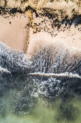 Aerial view of the baltic sea crashing on the black sand of the beach in Estonia. - AAEF02085