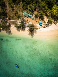 Luftaufnahme eines Bootes, das im paradiesischen Meer in der Nähe von kleinen Häusern am Strand im Chao-Mai-Nationalpark in Thailand vertäut ist. - AAEF02179