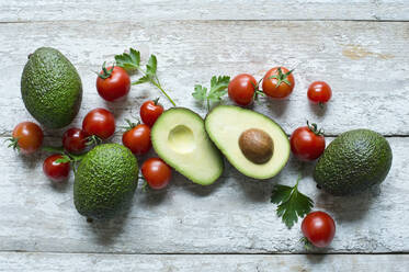 Direkt über der Aufnahme von Avocados mit Tomaten und Petersilie auf einem Holztisch - ASF06487