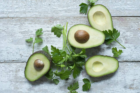 Unmittelbar über der Aufnahme von Avocados mit Petersilie auf einem Holztisch, lizenzfreies Stockfoto