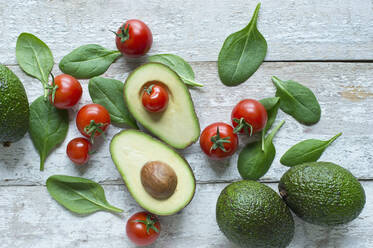 Directly above shot of avocados with tomatoes and spinach on wooden table - ASF06491