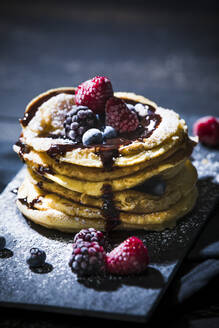 Pancakes with berries on plate at table - MAEF12925