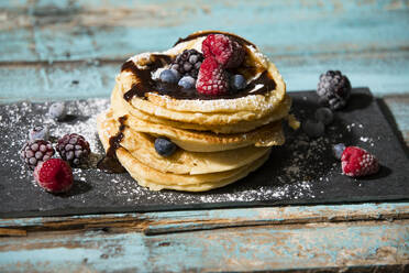 Close-up of pancakes with chocolate sauce and various berries on table - MAEF12926