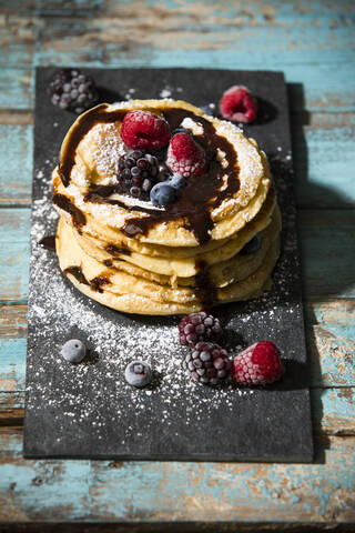 Pfannkuchen mit Schokoladensauce und verschiedenen Beeren auf dem Tisch, lizenzfreies Stockfoto