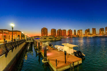 Luxuriöse Yachten und Boote im Hafen von Porto Arabia bei Nacht, The Pearl-Qatar, eine künstliche Insel als Wahrzeichen der Stadt und beliebtes Touristenziel im Persischen Golf, Doha, Katar, Naher Osten - RHPLF00364