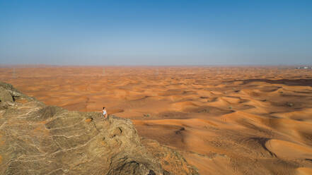 Luftaufnahme eines Mädchens auf dem Gipfel eines felsigen Berges bei der Camel Rock Desert Safari in den Vereinigten Arabischen Emiraten. - AAEF02248