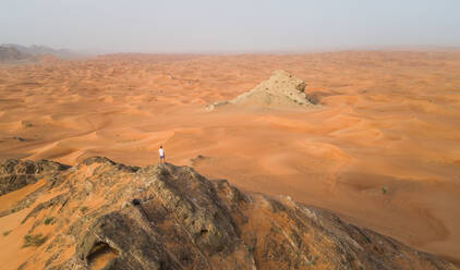 Luftaufnahme eines Mannes auf dem Gipfel eines felsigen Berges bei der Camel Rock Desert Safari in den Vereinigten Arabischen Emiraten. - AAEF02251