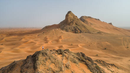 Luftaufnahme eines Mannes auf einem felsigen Berg bei der Camel Rock Desert Safari in den Vereinigten Arabischen Emiraten. - AAEF02252