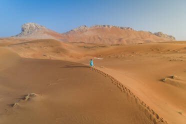 Luftaufnahme einer Frau, die in der Wüste spazieren geht, Dubai, Vereinigte Arabische Emirate. - AAEF02370