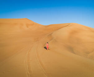 Luftaufnahme einer attraktiven Frau in einem roten Kleid in einer Wüstenlandschaft, V.A.E. - AAEF02440