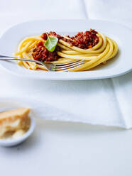 Makkaroni mit Bolognesesoße in einem Teller auf dem Tisch - PPXF00226