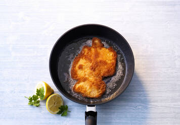 Wiener Schnitzel in frying pan forming Germany map at table - PPXF00227