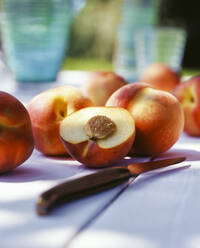 Close-up of fresh peaches with knife on table - PPXF00230