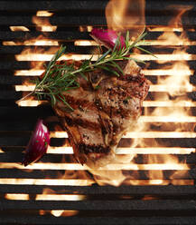 Directly above shot of fresh steak grilling and onion with herb on barbecue - KSWF02061